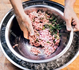 Перемешайте ингредиенты для домашней колбасы руками, используйте движение как при замесе теста, пока мясо и специи не перемешаются равномерно.